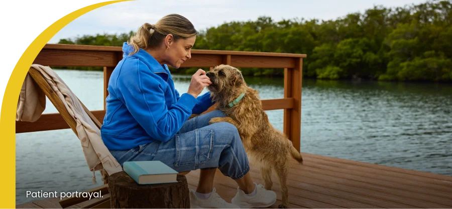 woman feeding her dog sitting at the dock