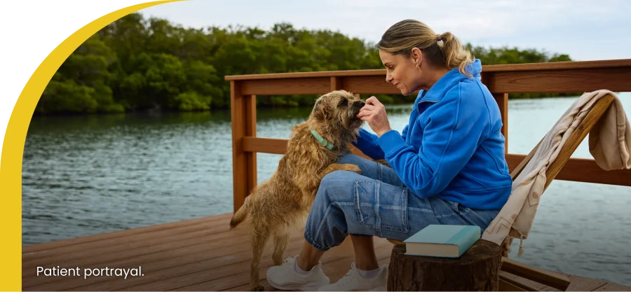 woman feeding her dog sitting at the dock